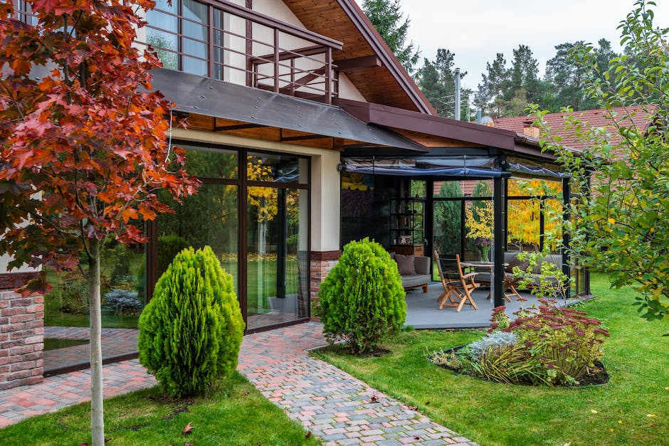 Exterior of contemporary house with cozy terrace and garden with bushes and trees on autumn day